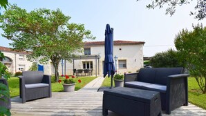 An outdoor deck with wicker furniture, a blue umbrella, and potted plants. - Gîte l'Ostalet de Sarron avec piscine, Brax - Lot et Garonne (BRAX)