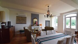 Un dormitorio con cama, chimenea, candelabro, escritorio y ventana.