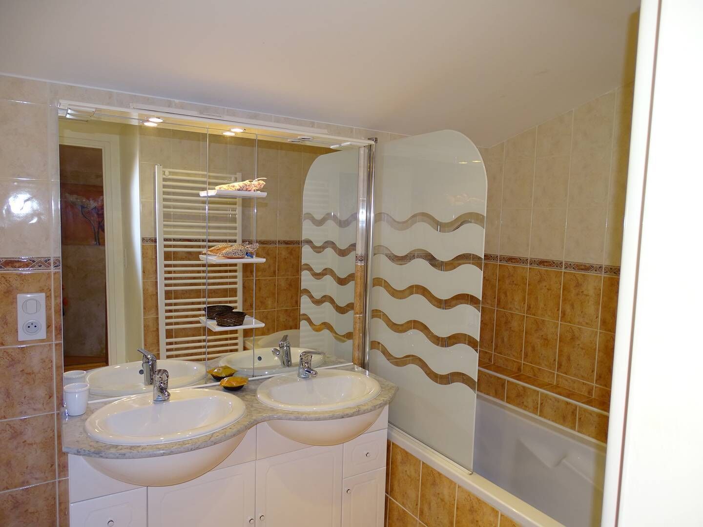 A bathroom with two sinks, a large mirror, and a shower area.