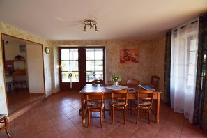A dining area with a wooden table and chairs, a ceiling light fixture, and a door leading to a balcony.