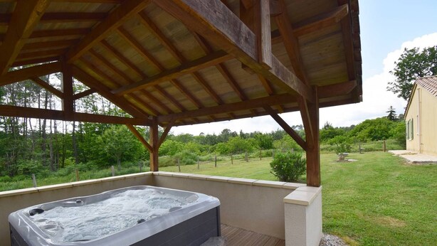 A hot tub under a wooden pergola with a view of a grassy yard and trees. - Gîte avec piscine et jacuzzi - Lot-et-Garonne (BLANQUEFORT SUR BRIOLANCE)