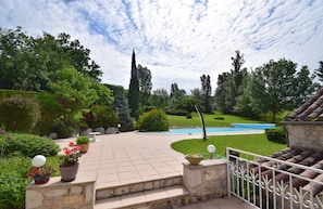 Un área exterior ajardinada con piscina, escalones de piedra y diversas plantas.