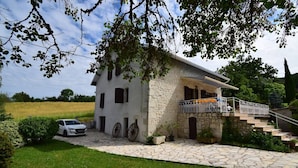 Una casa in pietra con un balcone e una scala che conduce a un portico coperto.