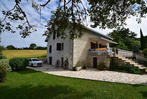 Una casa de piedra con balcón y una escalera que lleva a un porche cubierto.