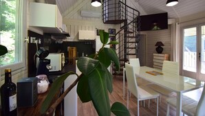 A modern kitchen with white cabinets, a central island, and a spiral staircase leading to an upper level.