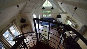 A high-ceilinged room with a staircase, a sofa, and a dining area.