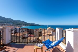 Ein Balkon mit Meerblick, ein Stuhl und ein Tisch mit einer Zeitschrift.