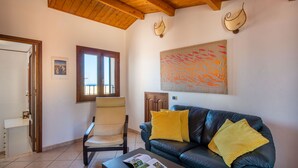 Un salon avec un canapé en cuir, un fauteuil, une table basse et un tableau accroché au mur.