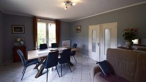 Ein Essbereich mit Tisch, Stühlen, einem Heizkörper, einem Ventilator und einer Couch.