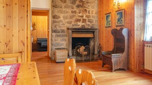 Una habitación acogedora con chimenea de piedra, paredes de madera, una silla de madera y una mesa de comedor.
