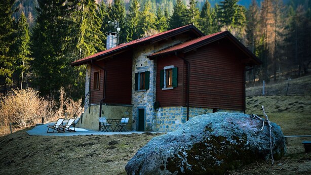 Eine rustikale Holzhütte mit Steinunterbau, umgeben von einem Wald.