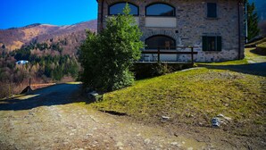 Une maison en pierre avec un toit en tuiles, un petit balcon et une vue sur un paysage montagneux.