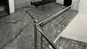 Una habitación con piso de mármol, baranda de metal, un banco negro y un ventilador de techo.