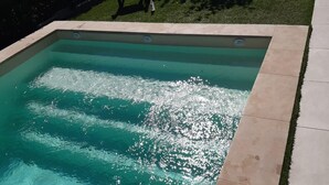 A rectangular swimming pool with a tiled edge and a grassy area in the background. - Villa Piscine vue Castelas (Rochefort-du-Gard)