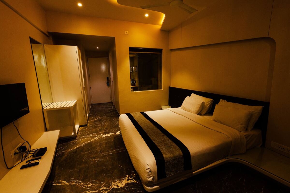 A hotel room with a bed, bedside table, and a TV.
