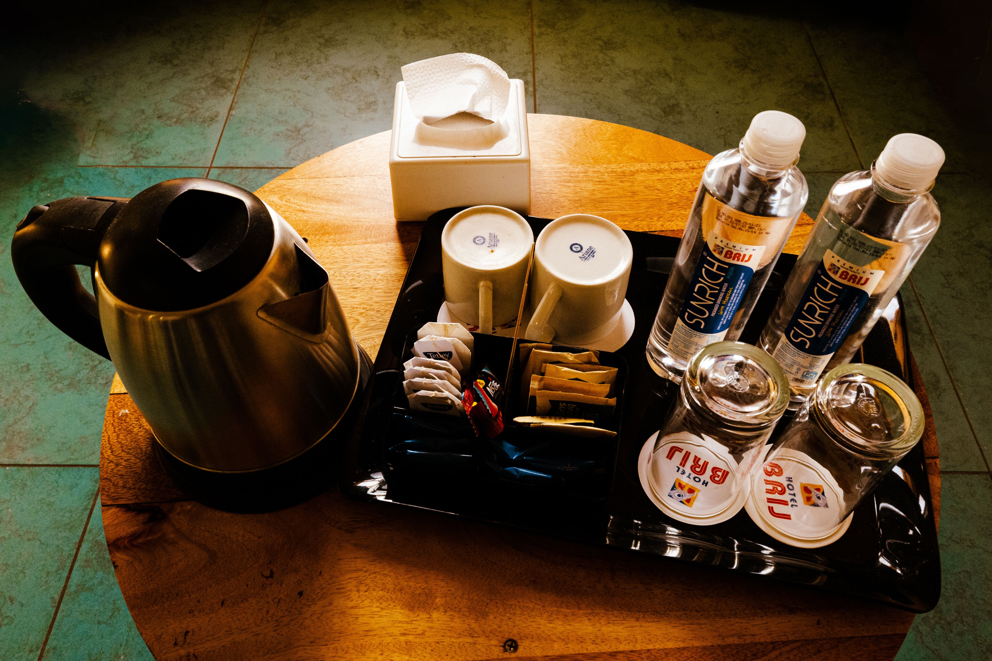 A tray with a coffee maker, cups, bottles, and jars, likely for a hotel room.