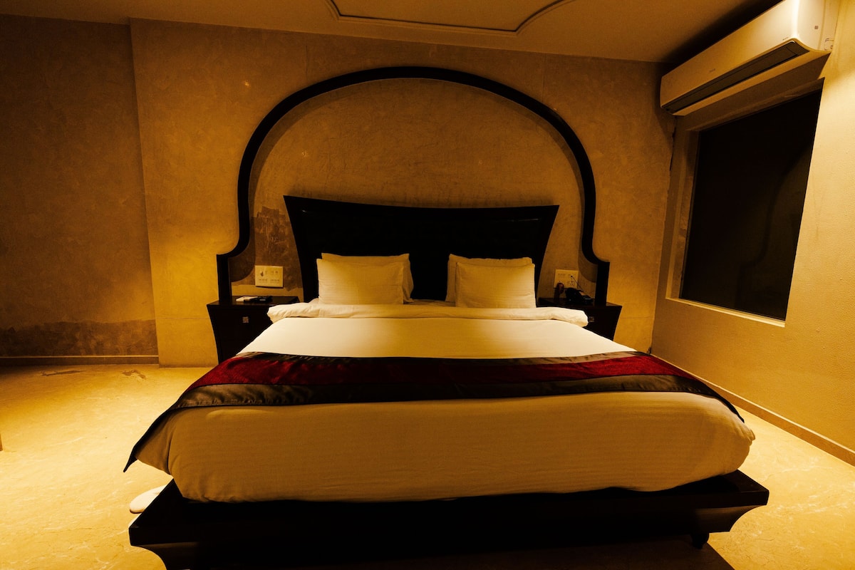 A bed with a headboard, bedside tables, and a window.