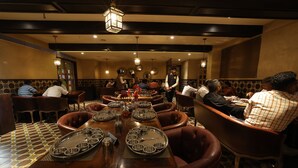 A restaurant with a long communal table, individual seating, and a patterned floor. - Hotel Brij Residency (Latur)
