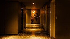 A hallway with a marble floor, recessed lighting, and doors on both sides. - Hotel Brij Residency (Latur)