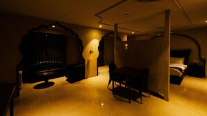A dimly lit room with a bed, a desk, and a chair. - Hotel Brij Residency (Latur)