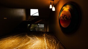A dimly lit room with a marble floor, a staircase, and a wall-mounted artwork. - Hotel Brij Residency (Latur)