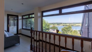 A spacious balcony with large windows overlooking a lake and greenery. - Beautiful family home with fantastic views over the Menai straits (Y Felinheli)