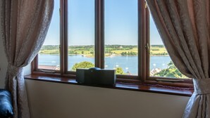 A room with a large window overlooking a lake, a wooden desk, and a chair. - Beautiful family home with fantastic views over the Menai straits (Y Felinheli)