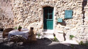 A stone building with a green door and a small table with chairs outside. - Medieval house - next to Château (Durban-Corbières)