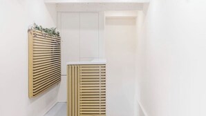 A narrow hallway with a white door and a radiator with horizontal slats. - Via del Centro (Oristano)