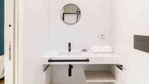 A compact bathroom with a white sink, mirror, and toilet. - Via del Centro (Oristano)
