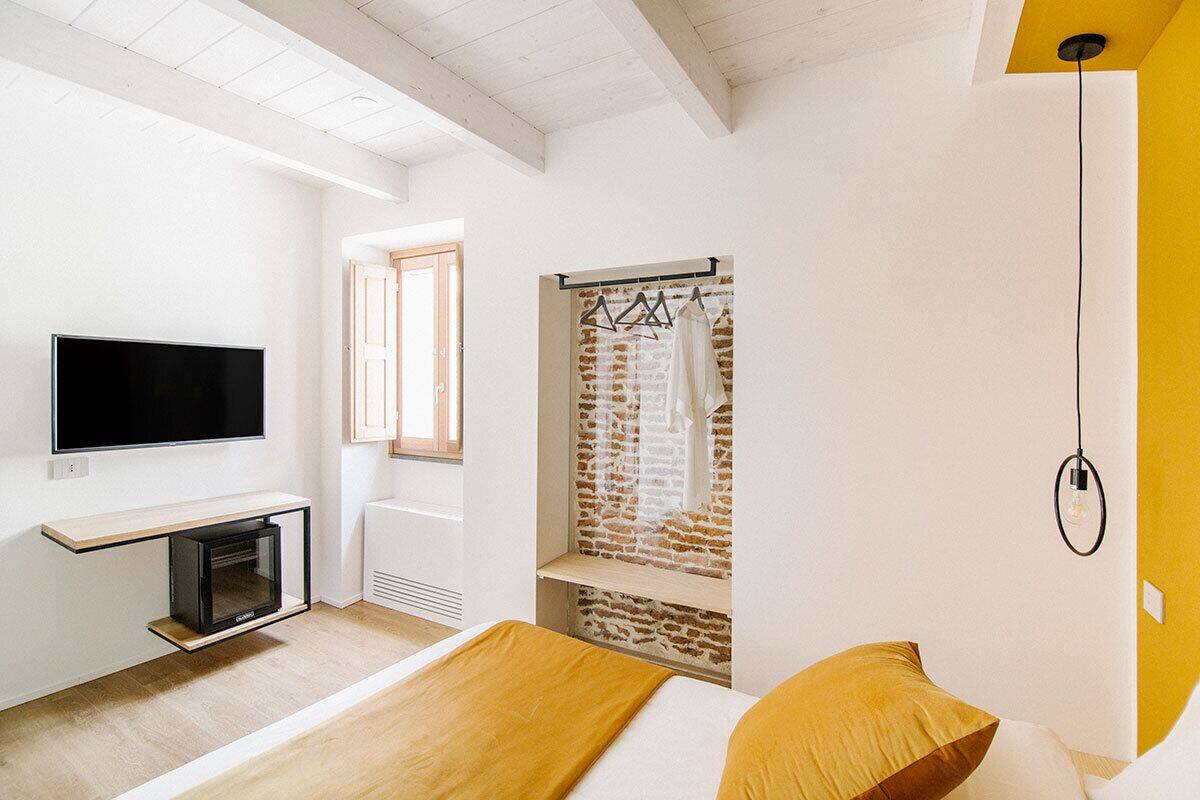 A modern bedroom with a TV, fireplace, and a brick wall feature.