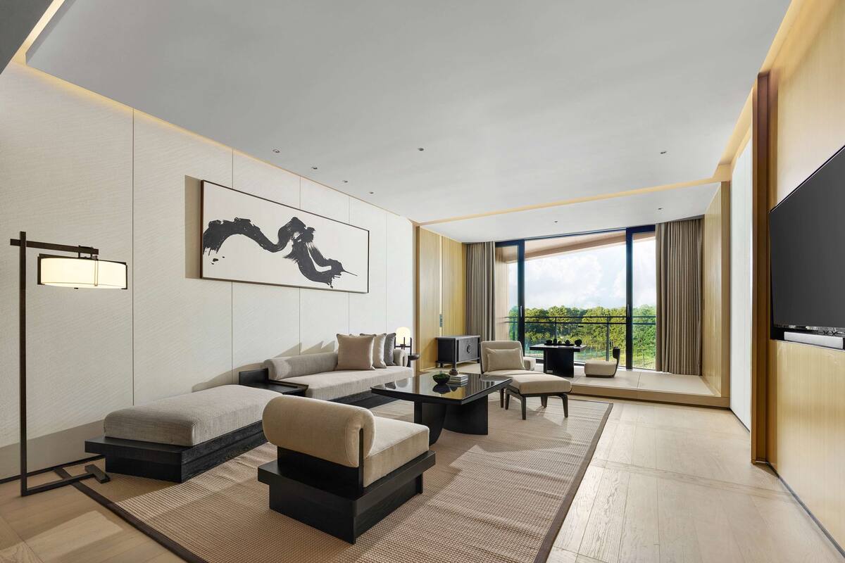 A modern living room with a sofa, armchair, coffee table, and a flat-screen TV.