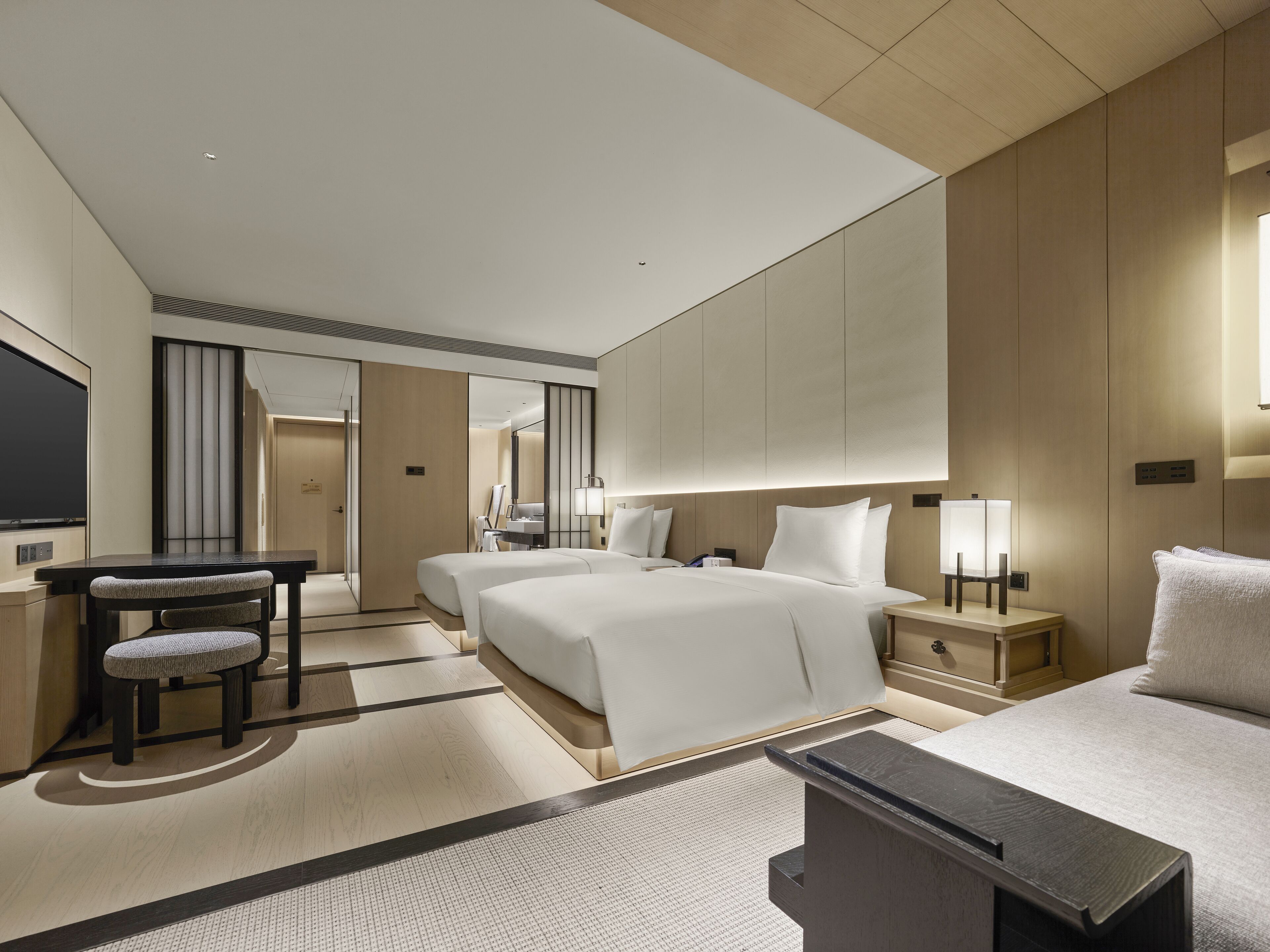 Una habitación de hotel moderna con dos camas, un escritorio y una silla.