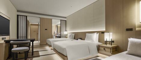A modern hotel room with two beds, a desk, and a chair.