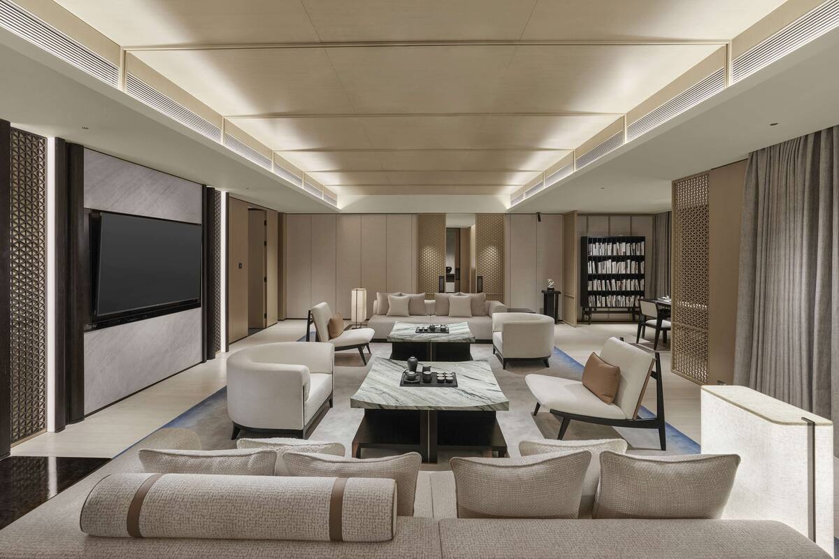 A spacious living room with a large flat-screen TV, comfortable seating, a coffee table, and a bookshelf.