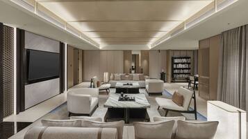 A spacious living room with a large flat-screen TV, comfortable seating, a coffee table, and a bookshelf.