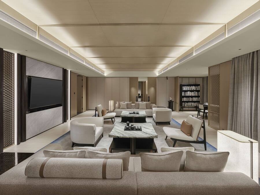 A spacious living room with a large flat-screen TV, comfortable seating, a coffee table, and a bookshelf.