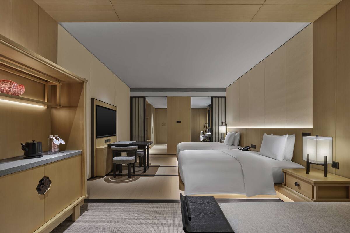 A modern hotel room with a large bed, a desk, and a TV.