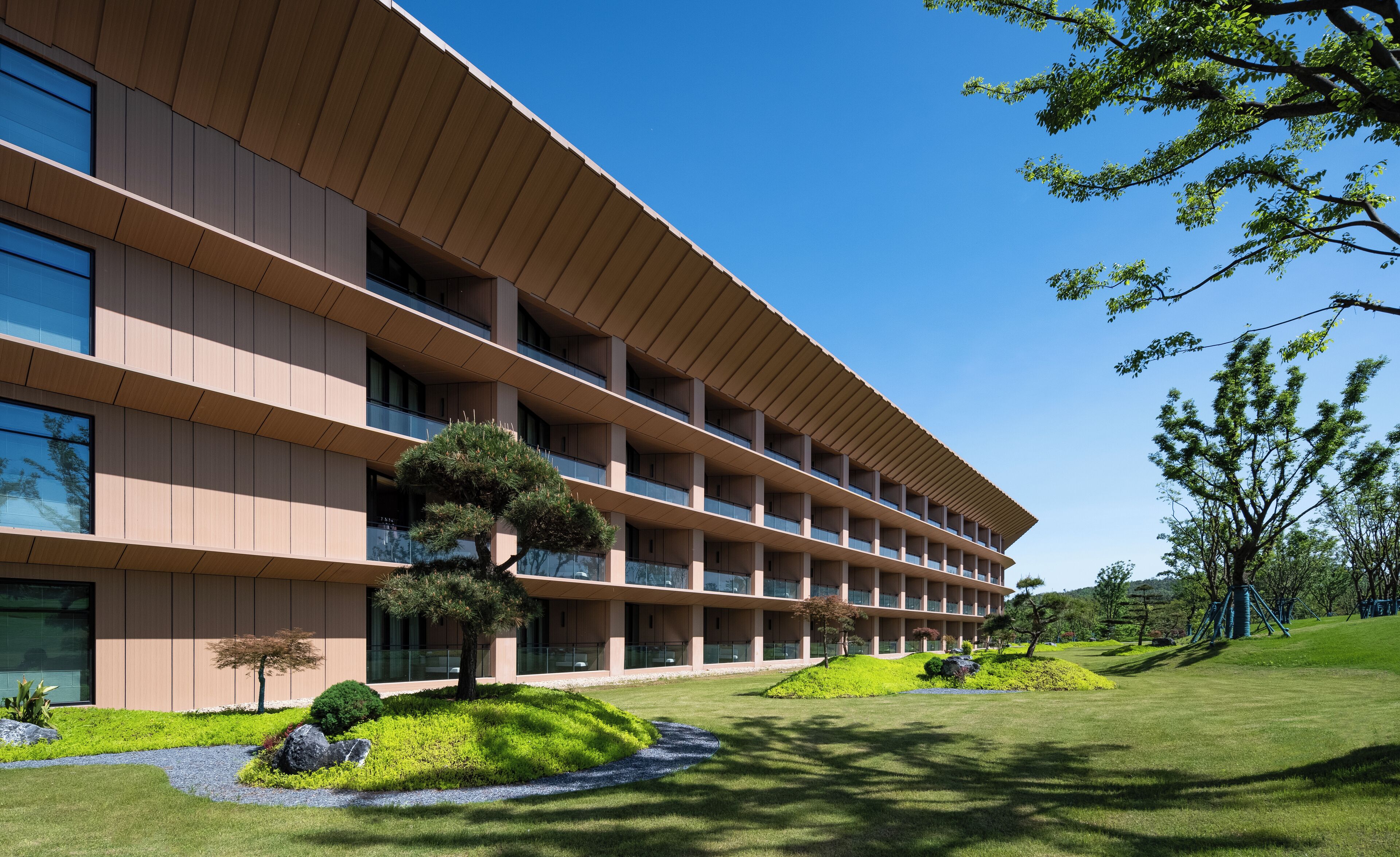 A modern multi-story building with a flat roof and large windows.