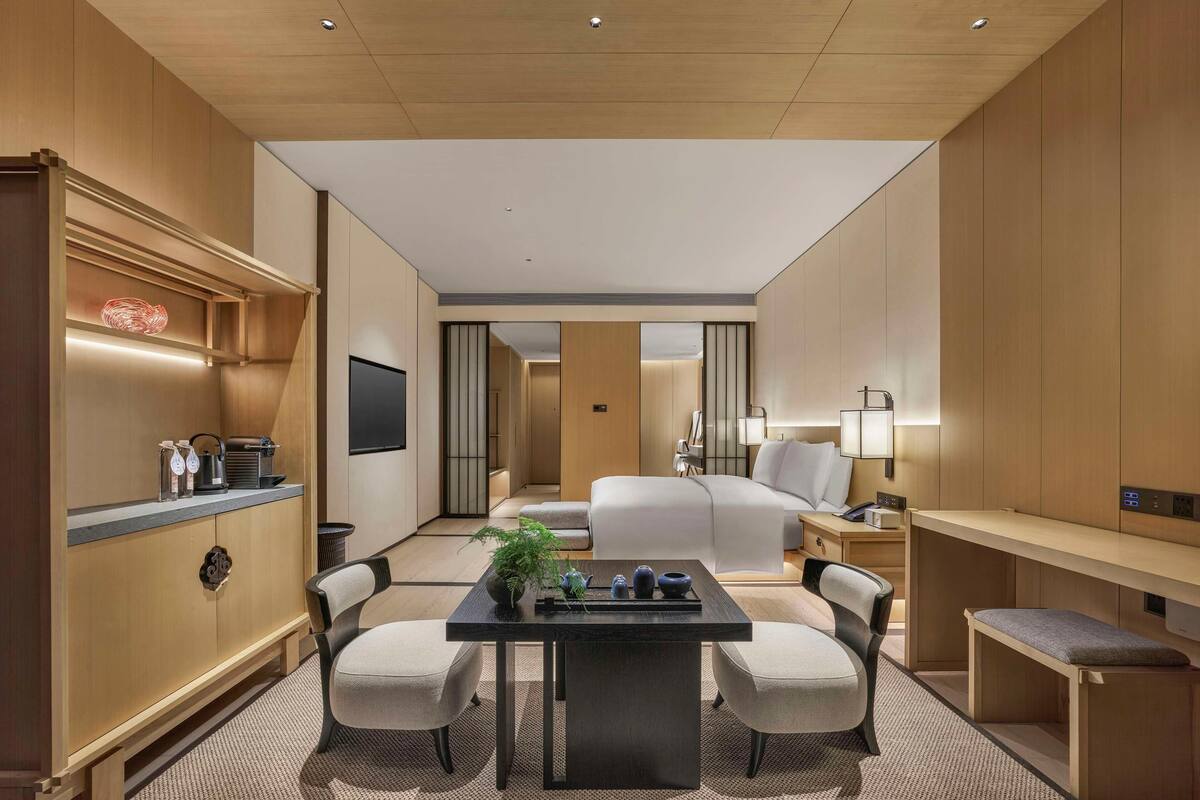 Une chambre d’hôtel équipée d’un lit, d’un bureau, de chaises, d’une télévision et d’un mini-bar.