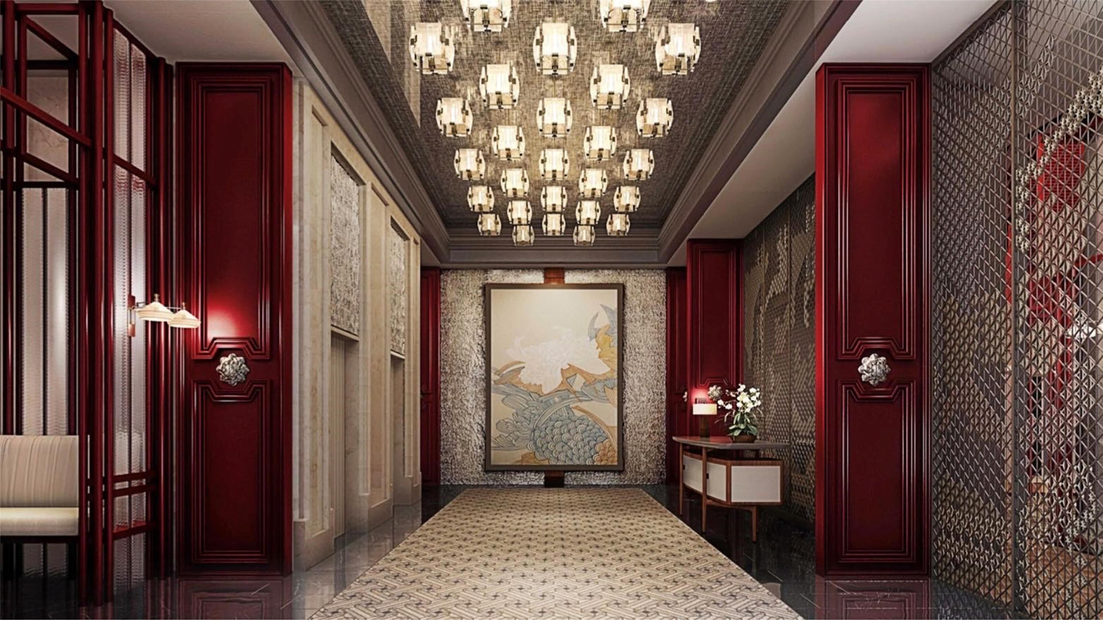 A hallway with a patterned carpet, a chandelier, and a painting on the wall.