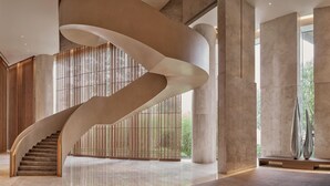 Un interior moderno con una escalera curva, ventanas amplias y una decoración minimalista.