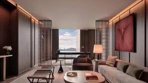 Una habitación de hotel moderna con sofá, mesa de centro, mesa de comedor y vista a la ciudad.