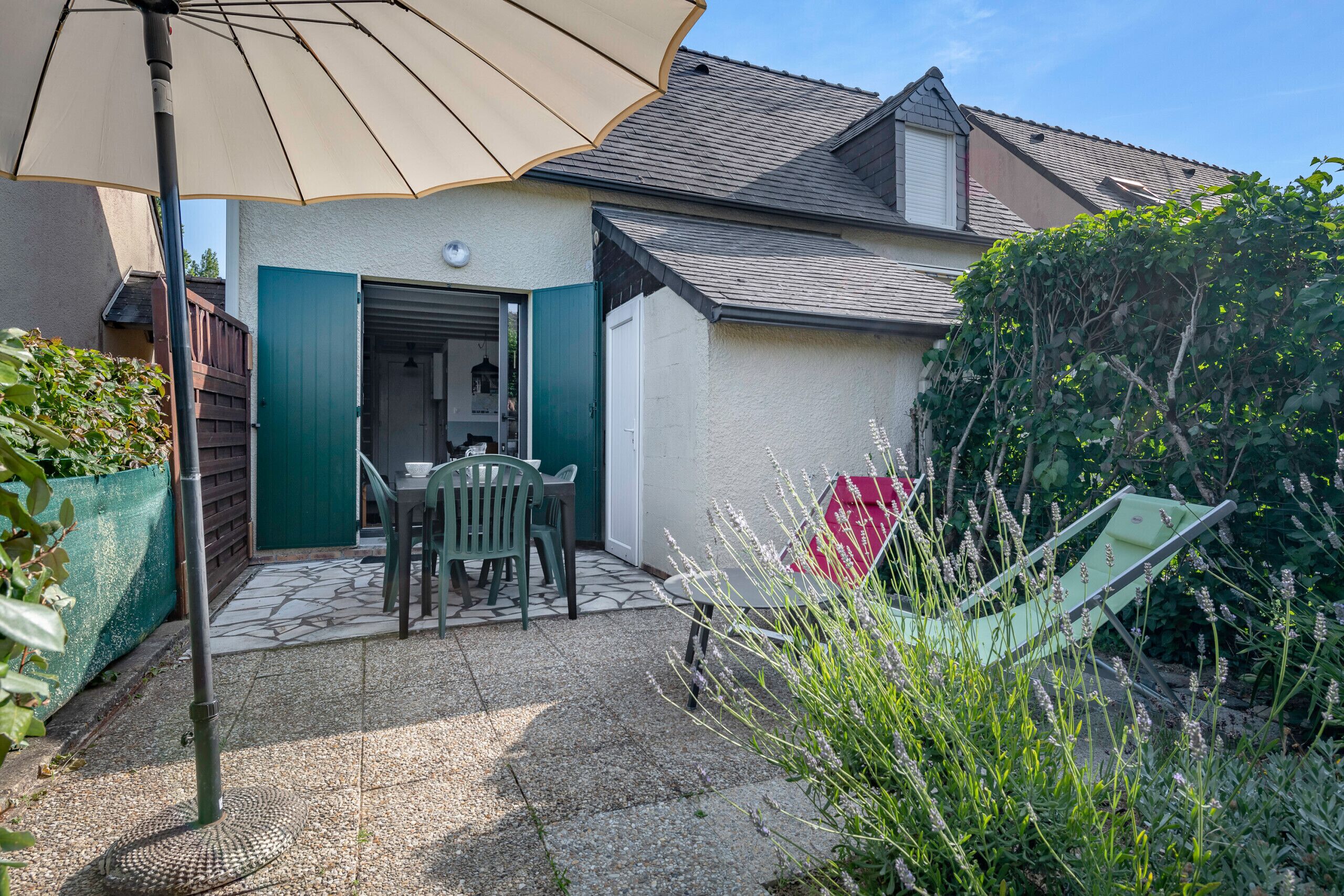 A patio with a table and chairs, a door, and a covered area with a table and chairs.