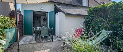 A patio with a table and chairs, a door, and a covered area with a table and chairs.