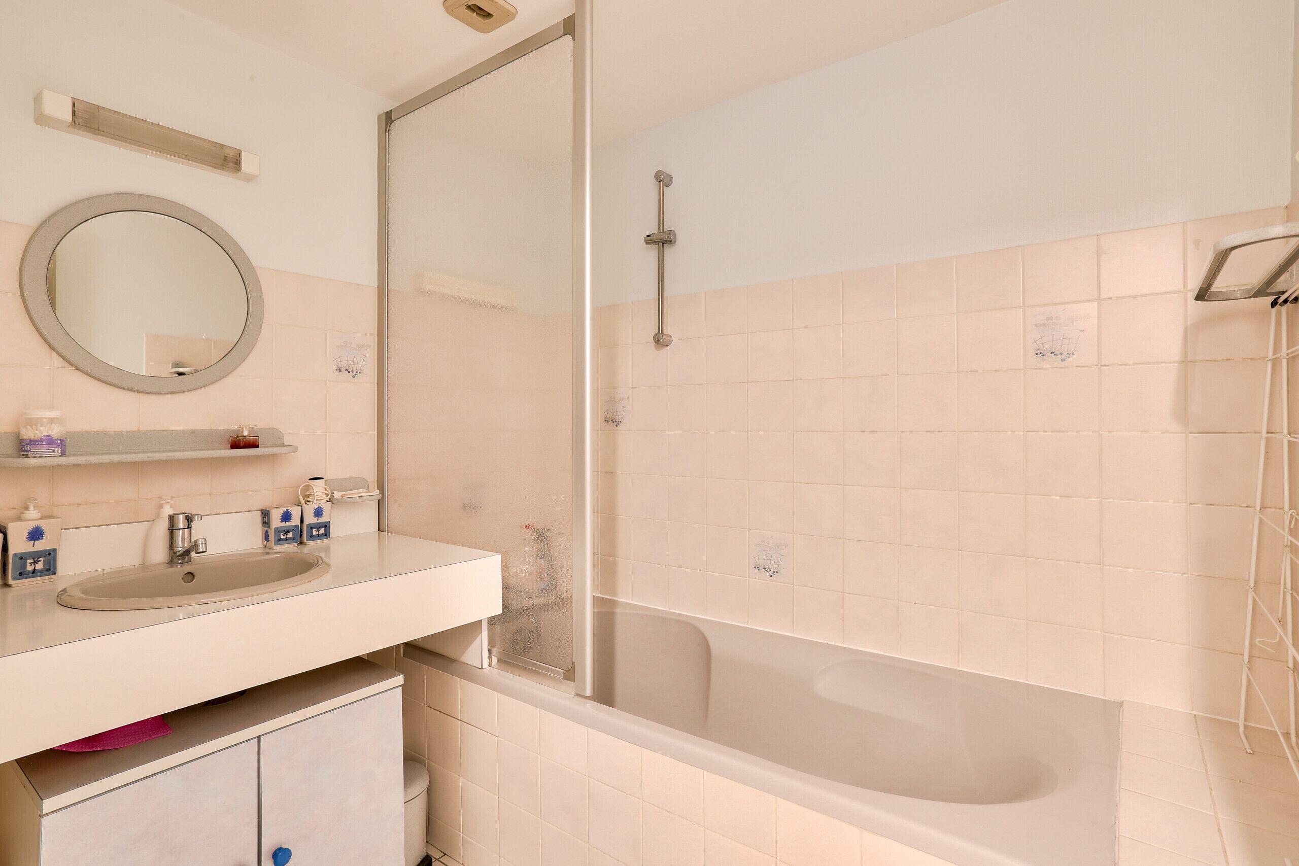 A bathroom with a sink, mirror, and bathtub.