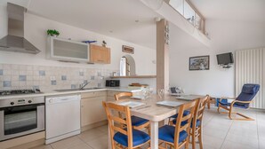 Una cocina moderna con comedor, que incluye estufa, lavavajillas, microondas y una mesa con sillas.