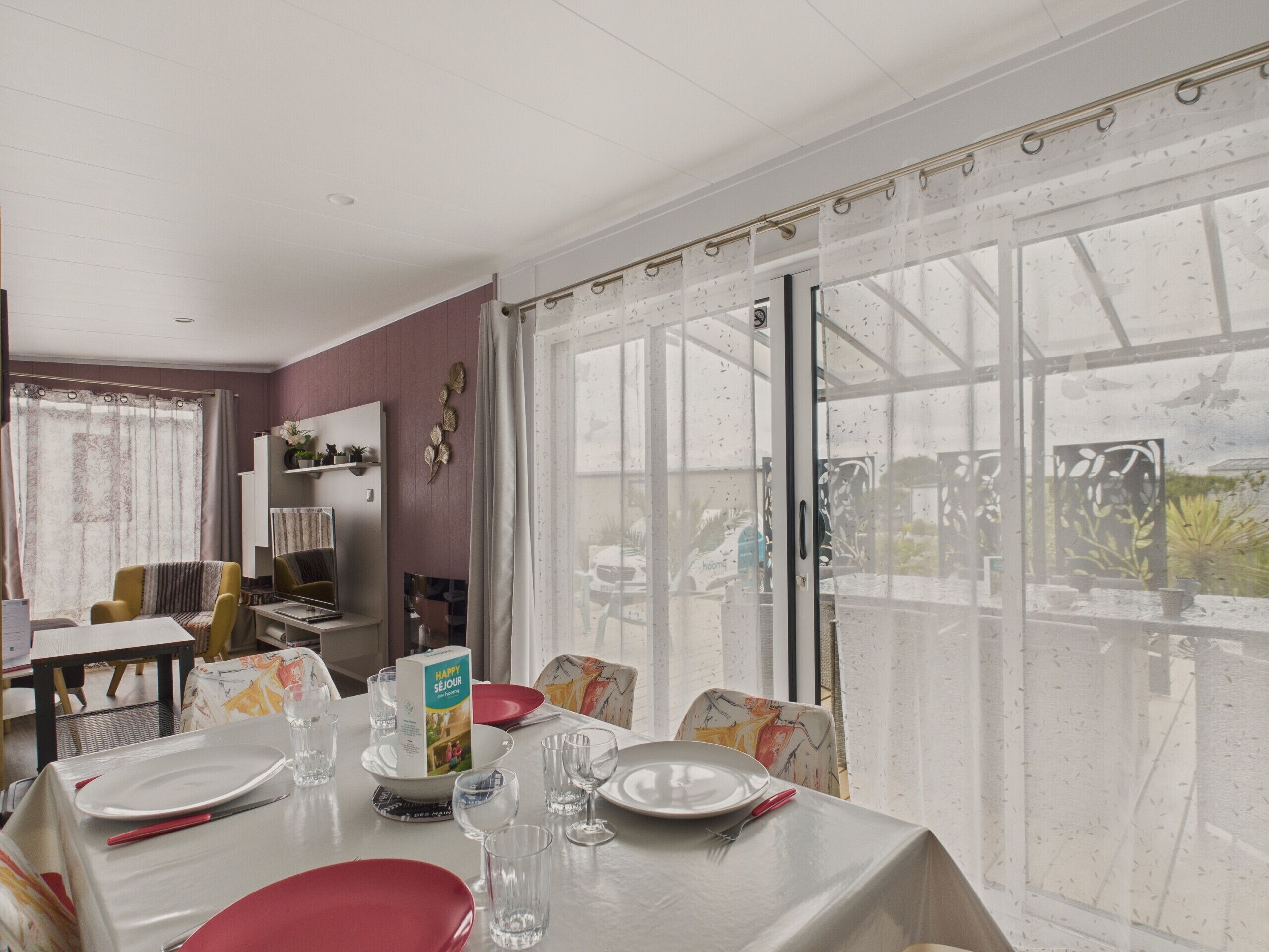 Un coin repas avec une table dressée pour quatre personnes, une bibliothèque et une vue à travers une porte vitrée.