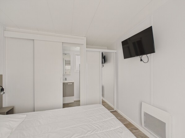 Ein modernes Hotelzimmer mit einem Bett, einem an der Wand befestigten Fernseher und einem Kleiderschrank.