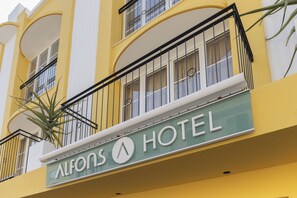 Ein Hotelschild mit Balkonen und einer Pflanze.